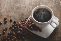 Cup of coffee alongside coffee beans.