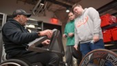 Man in wheelchair talking with engineering students.
