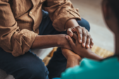 Two people holding hands in a show of comfort and support.