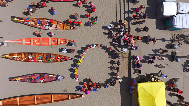 Aerial picture of beach with canoes lined up and people standing in circle
